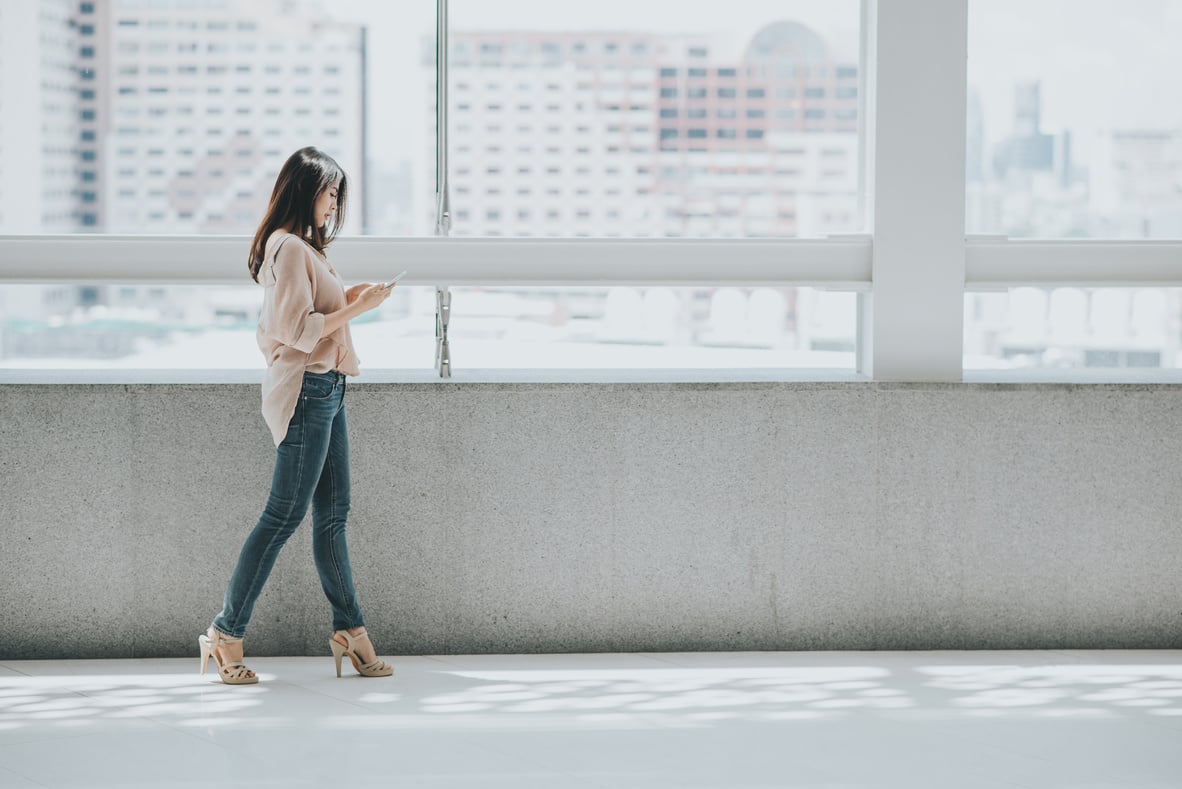 Woman Using Smartphone  While Walking In Office Building